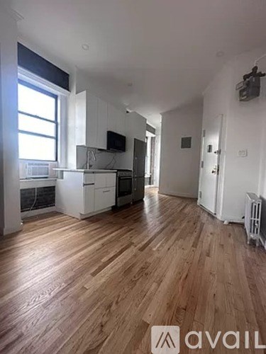 A spacious room with wooden flooring and white walls.