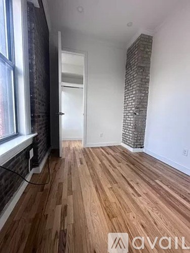A room with wooden flooring and a brick pillar.