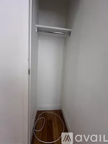 A small, empty room with a wooden floor and a white wall.