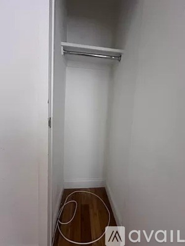 A small, empty room with a wooden floor and a white wall.