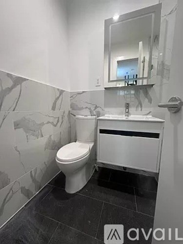 A bathroom with a toilet, sink, and mirror.