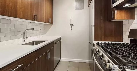 A kitchen with a stove, sink, and cabinets.