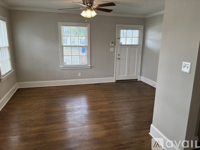 A room with a ceiling fan and wooden flooring.