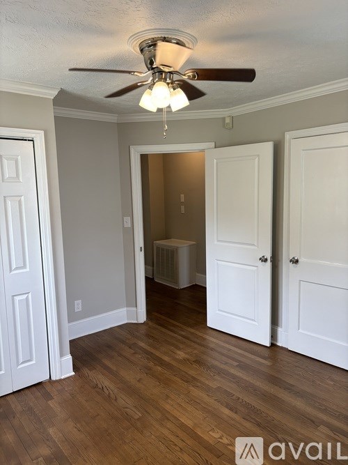 A room with a ceiling fan and wooden floors.