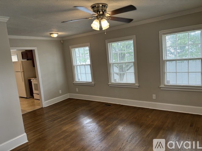 A room with a ceiling fan and two windows.