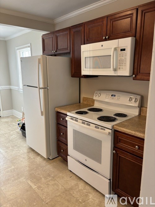 A kitchen with a white refrigerator, white stove, and brown cabinets.