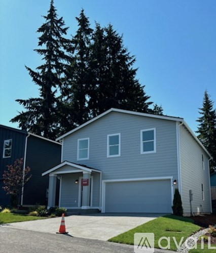 A house with a garage and a tree in front.