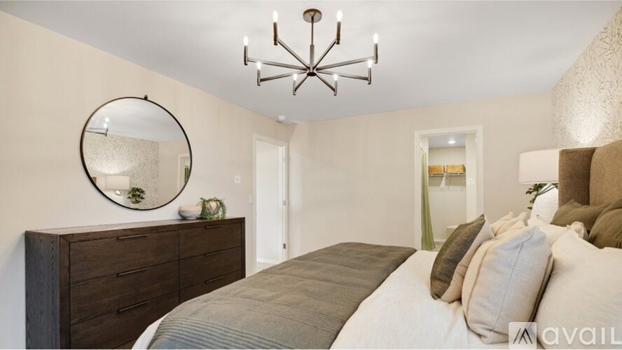 A bedroom with a large bed, a chandelier, and a mirror on the wall.