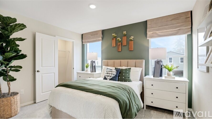 A bedroom with a large bed, a nightstand, and a plant.