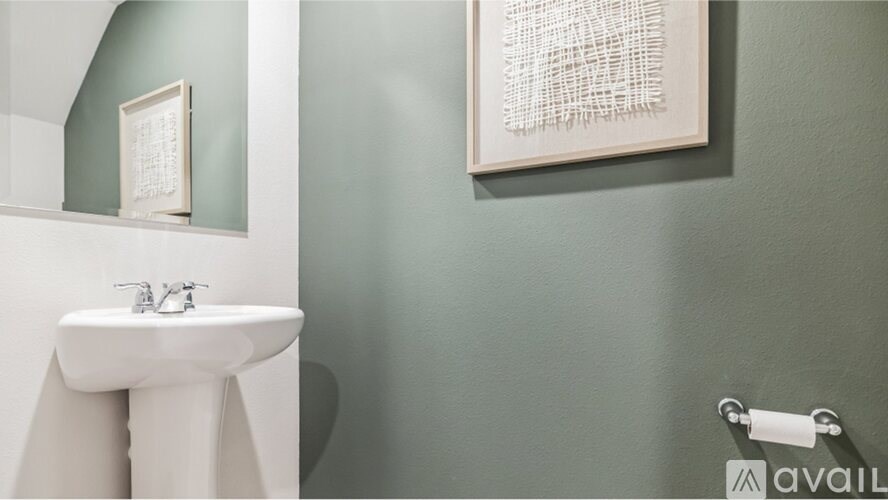 A bathroom with a white sink and a green wall.