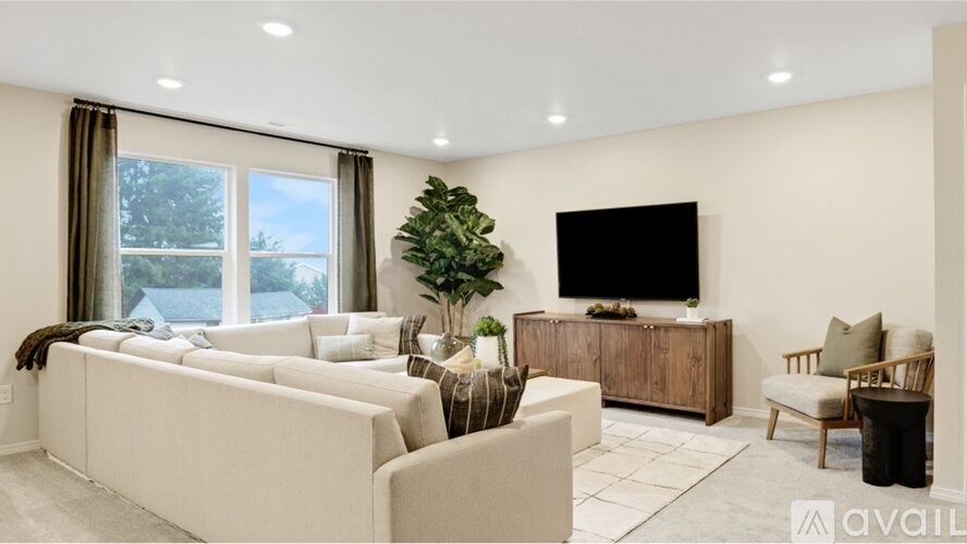 A living room with a large couch, a television, and a plant.
