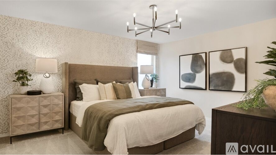 A bedroom with a large bed, a chandelier, and a side table with a lamp.