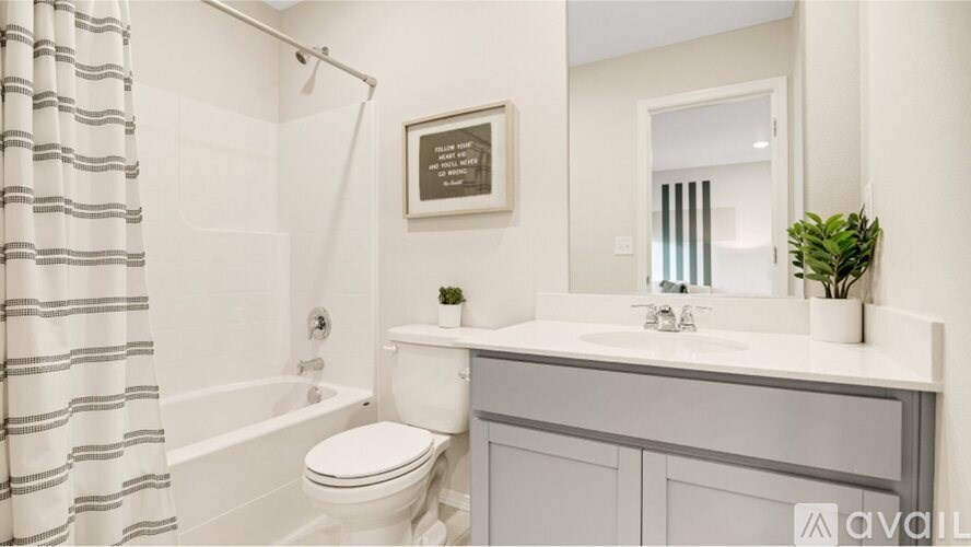 A bathroom with a white toilet, a white sink, and a white bathtub with a striped shower curtain.