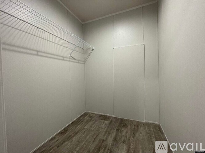 A small, empty room with wood flooring and white walls.