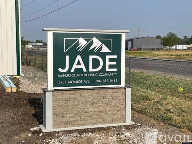 A sign for Jade Manufactured Housing Community stands in front of a building.