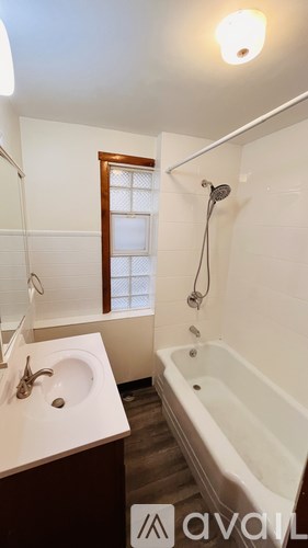 A bathroom with a tub, sink and window.