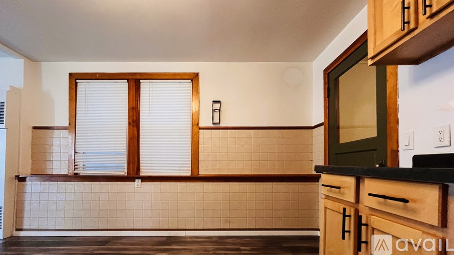 A kitchen with wooden cabinets and a tiled wall.