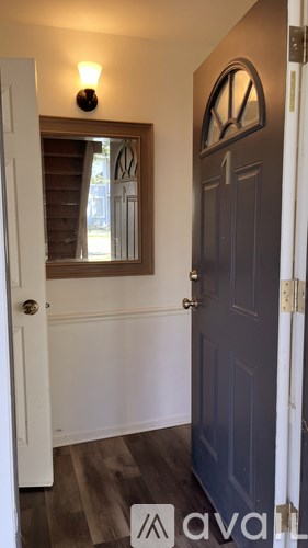 A white door with a mirror above it and a light on the wall.