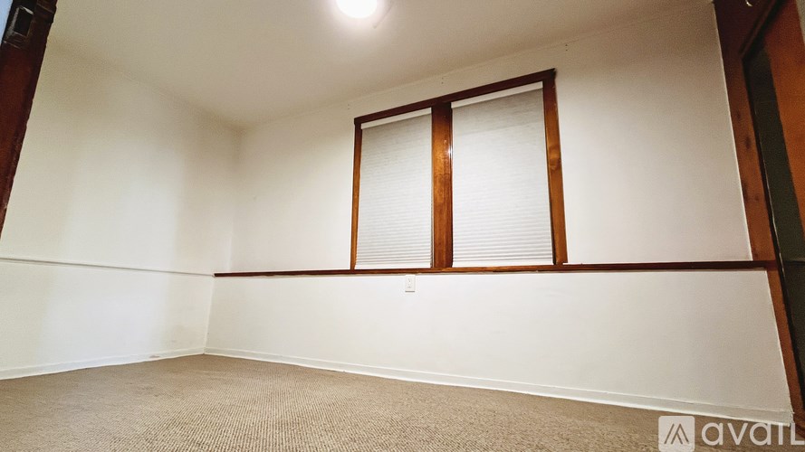 A room with a carpeted floor and a window with blinds.