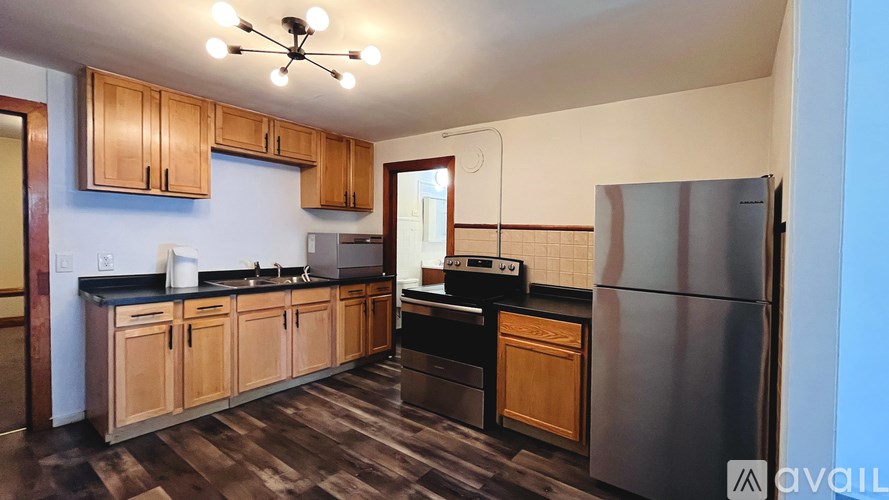A kitchen with wooden cabinets and a stainless steel refrigerator.