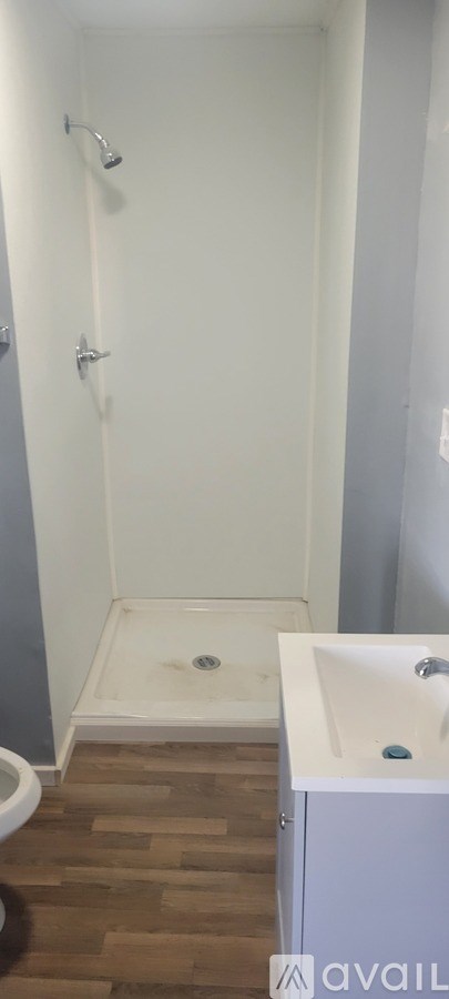A white bathroom with a wooden floor and a white sink.