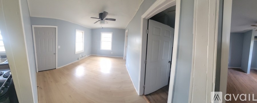 A spacious room with a ceiling fan and wooden flooring.