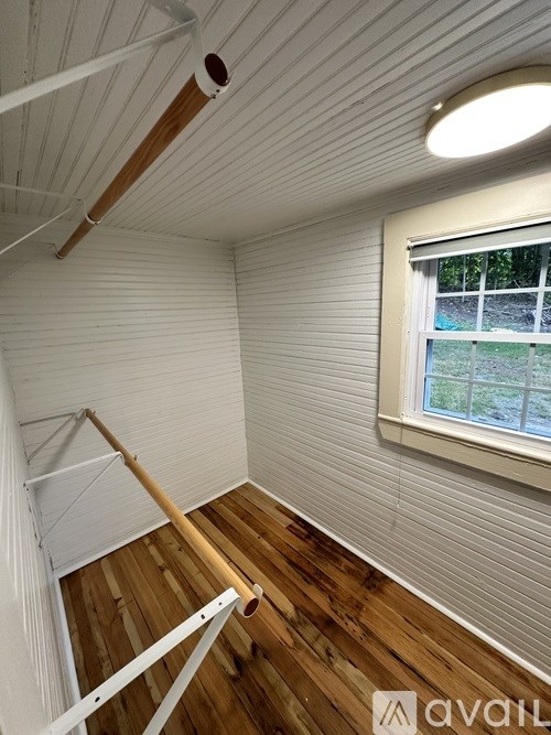 A room with wooden floors and a window with a view of a garden outside.