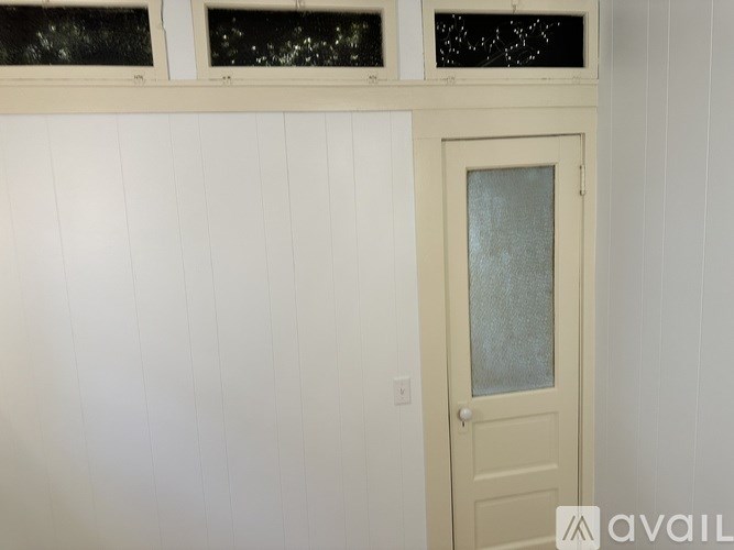 A white door with a glass window is in a room with white walls.