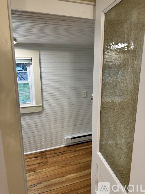 A room with a window covered by blinds and a wall heater.