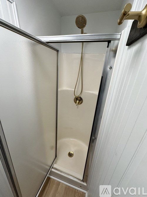 A white bathroom with a gold shower head and a white shower curtain.