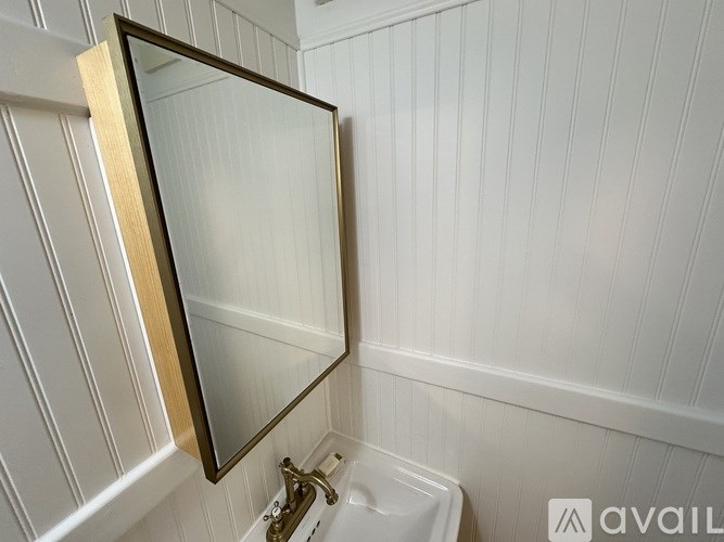 A bathroom with a white sink and a mirror with a wooden frame.