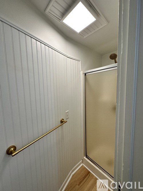 A bathroom with a glass shower door and a gold shower rod.