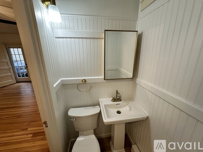 A bathroom with a toilet, sink, and mirror.