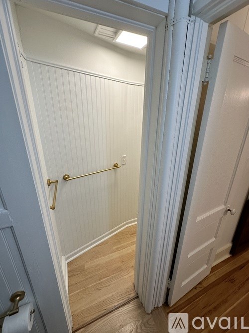 A white door with a gold handle is open.
