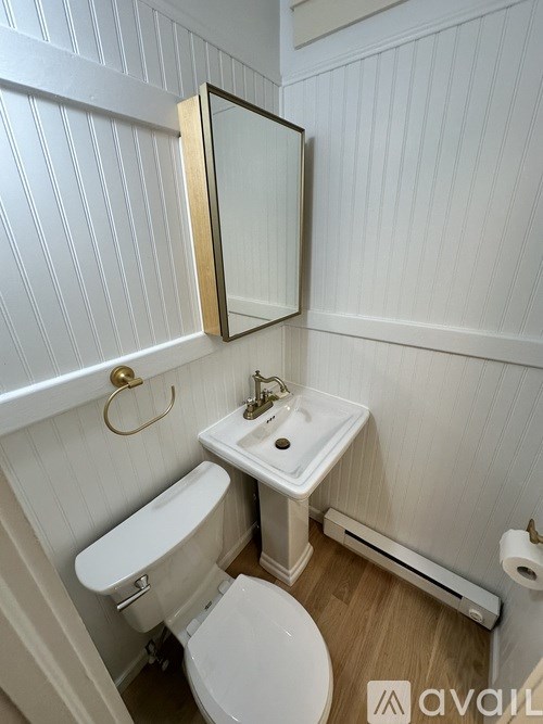 A white toilet with a sink and mirror in a bathroom.
