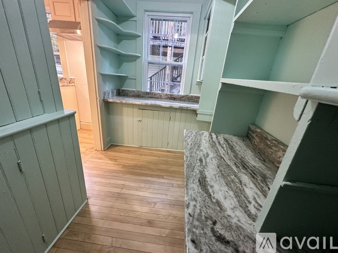 A room with wooden floors and a window with a view of a building outside.