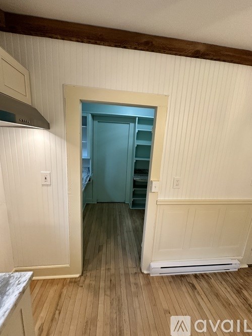 A room with a white wall and a wooden floor.