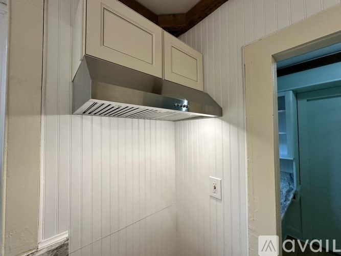 A wall-mounted range hood is installed above a white wall.