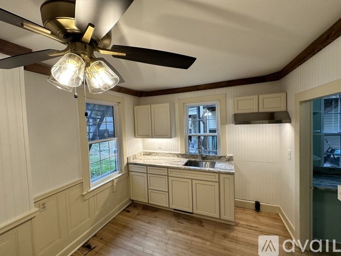 A kitchen with a ceiling fan and wooden floors.