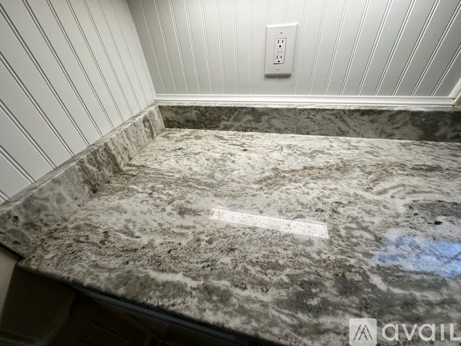 A marble countertop with a white outlet on the wall.