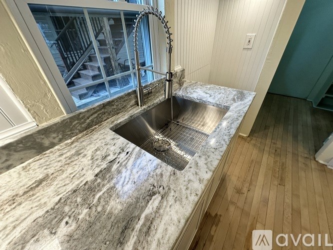 A modern kitchen with a marble countertop and a stainless steel sink.