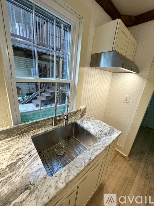 A kitchen with a marble countertop and a window overlooking a staircase.