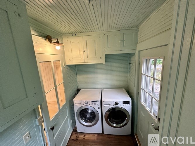 A laundry room with two washing machines and a window.