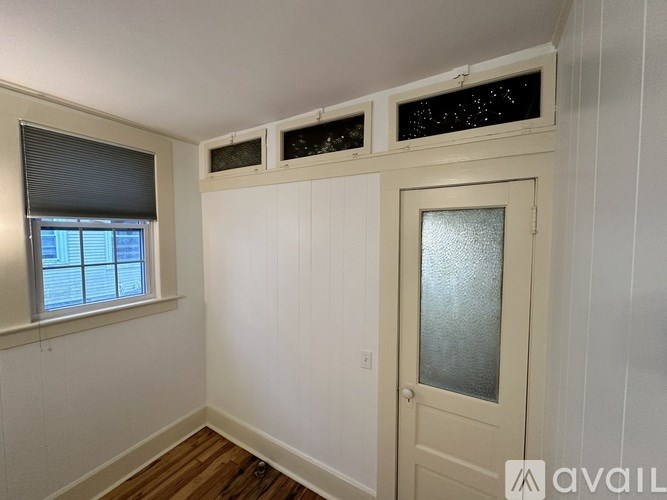A room with a window, wooden floors, and a door.