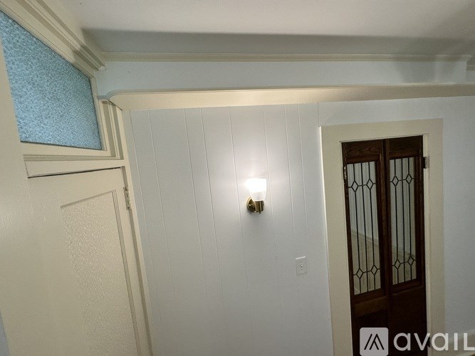 A white door with a window above it and a light switch on the wall.