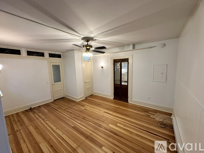 A room with wooden flooring and a ceiling fan.