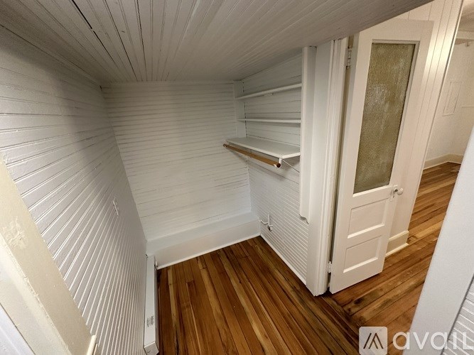 A white room with wooden floors and a white door.