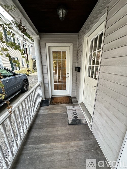 A white door with a window above it and a mat on the floor.