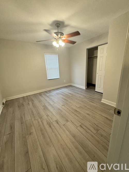 A room with a ceiling fan and wooden flooring.