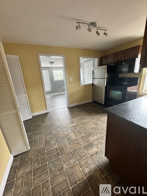 A kitchen with a black counter top and a tiled floor.